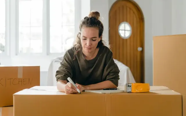 Frau notiert Umzugsdetails an einem Karton